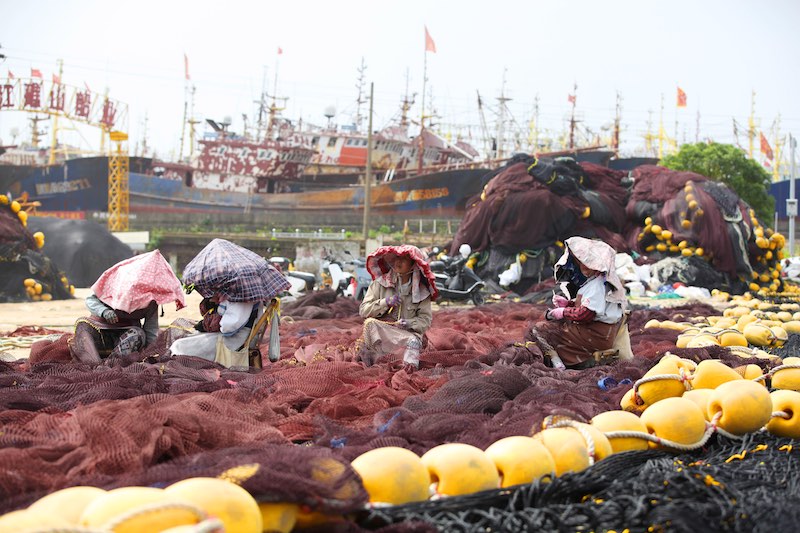 Pas de pêche, encore du travail : être occupés à repriser les filets de pêche