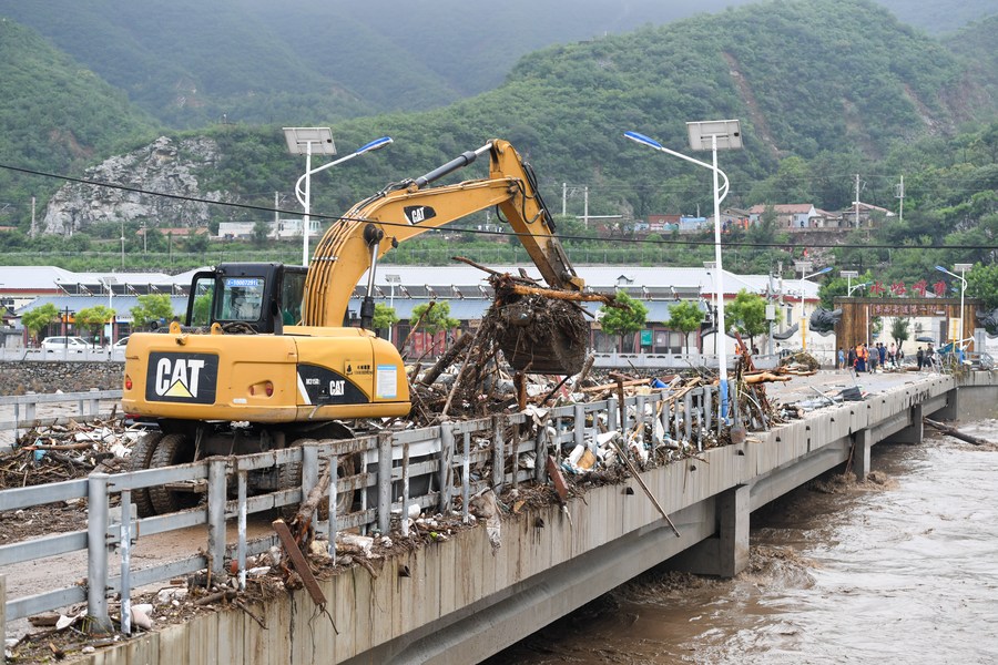 Une pelleteuse enlève les débris et les détritus accumulés sur un pont du village de Shuiyuzui, dans l'arrondissement de Mentougou, touché par les inondations, à Beijing, capitale chinoise, le 1er ao?t 2023. (Photo : Ju Huanzong)