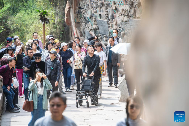 Des touristes visitent le site touristique des sculptures rupestres de Dazu à Chongqing