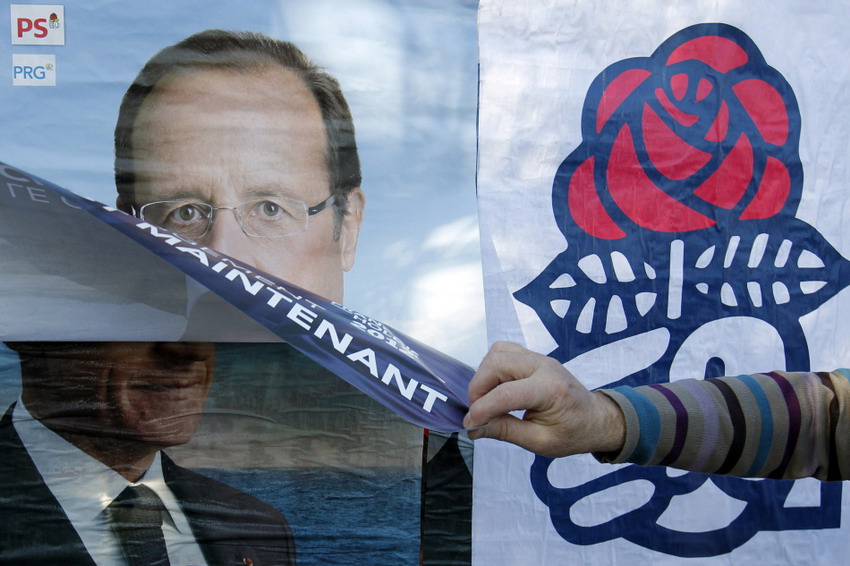 Le 12 avril 2012, un partisan du parti socialiste colle une affiche de leur candidat Fran?ois Hollande sur celle du président Nicolas Sarkozy. REUTERS/Stephane Mahe