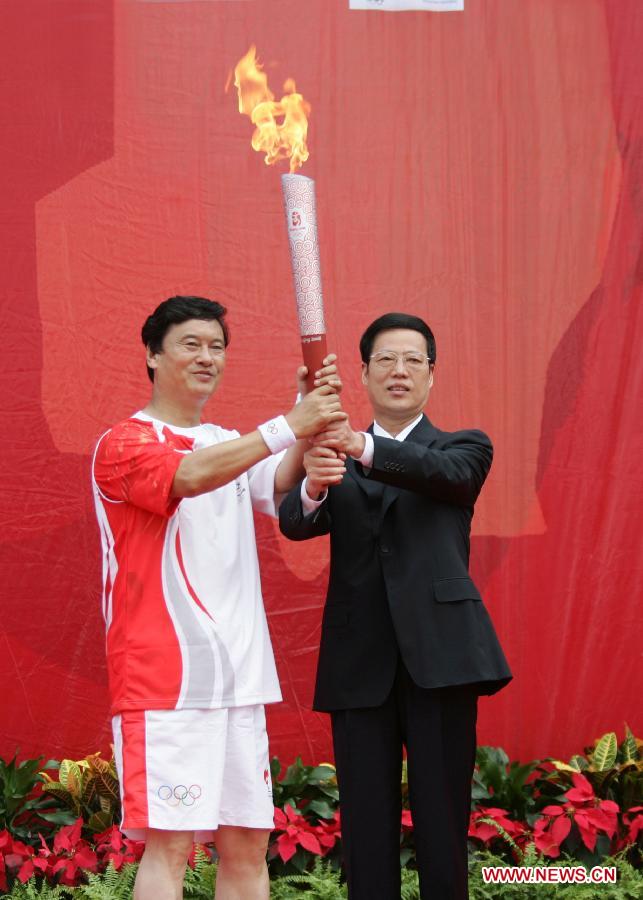 Photo d'archive prise le 1er ao?t 2008 montrant Zhang Gaoli (à droite) remettant la torche olympique au travailleur national modèle Kong Xiangrui dans la municipalité de Tianjin. (Photo : Song Ziming)