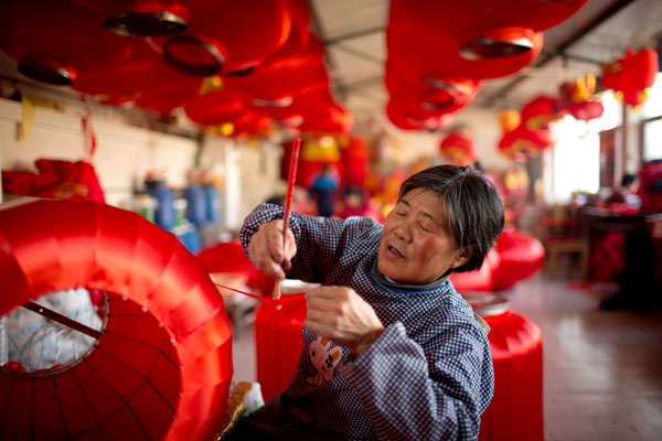 Le 26 janvier, dans le village de Hongmiao, situé à Beijing dans le district de Huairou, Yan Wanqin, agée de 64 ans, brosse et colle un morceau de soie rouge. C'est est la plus ancienne ouvrière de l'atelier des lanternes du village. Photos par Kuang Linhua/China Daily 