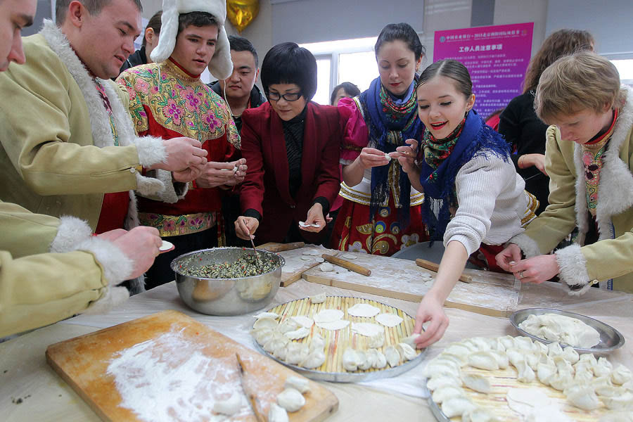 Dix couples étrangers venus de six pays, dont la Grèce et la Russie, déguisés avec des costumes chinois, apprennent à faire des raviolis chinois dans le Parc de Chaoyang à Beijing, le 14 février 2013. [Photo Cheng Gong / China Daily]