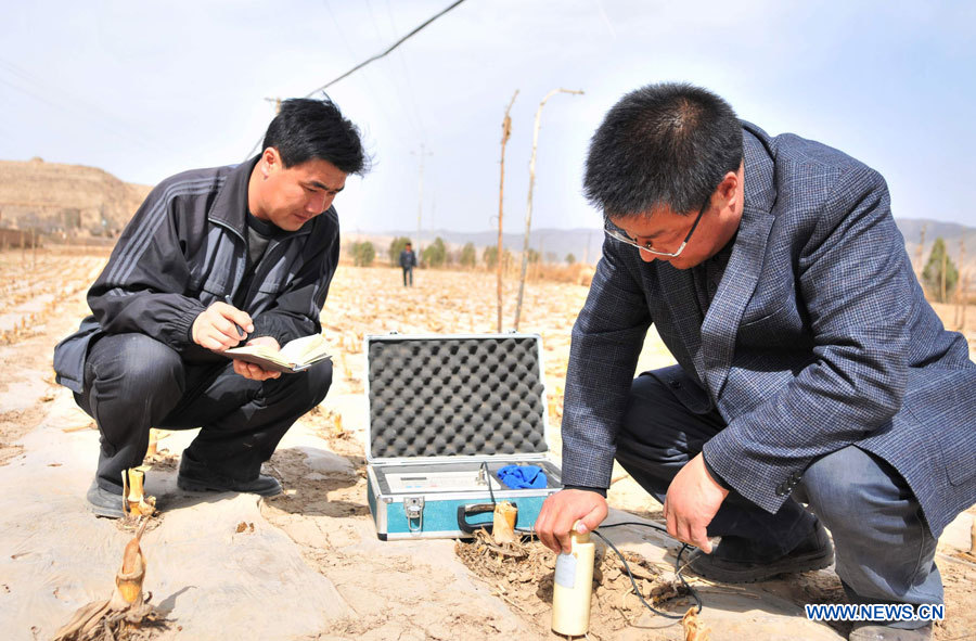 Un scientifique nommé Xing Guo (à droite) contr?le la teneur en eau des sols dans un champs de ma?s du village de Qingshui dans le district de Lujiagou, de la ville de Dingxi, dans la province chinoise du Gansu (nord-ouest), le 28 mars 2013. Au total, 650.000 habitants manquent d'eau potable dans la province du Gansu en raison de la sécheresse. (Photo : Chen Bin)