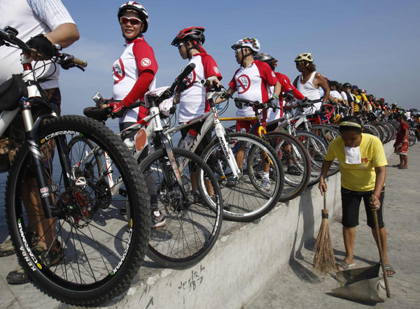 Un groupe de cyclistes avec leurs vélos alignés sur un mur bordant la mer, pour prendre part à l'événement ? Sauver la baie de Manille? lors des célébrations de la Journée de la Terre à Manille, le 21 avril 2013. [Photo/agences]