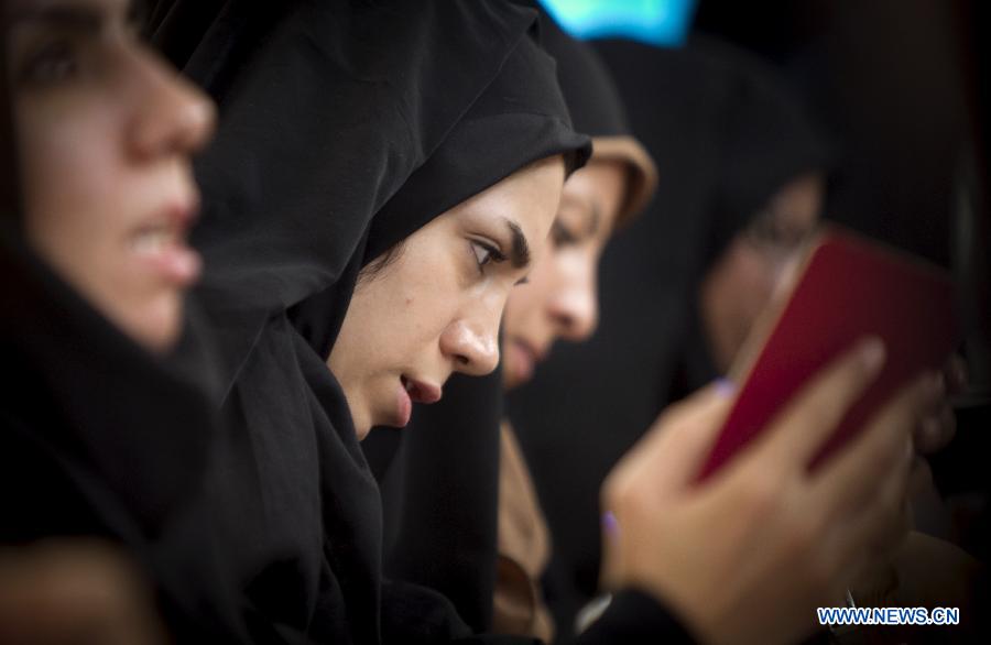 Une femme vérifie les papiers d'un électeur à un bureau de vote dans le nord de Téhéran, en Iran, le 14 juin 2013. Le dirigeant suprême de l'Iran, l'ayatollah Ali Khamenei, a voté à l'élection présidentielle iranienne et déclaré l'ouverture du scrutin vendredi matin. (Photo: Xinhua/Ahmad Halabisaz) 