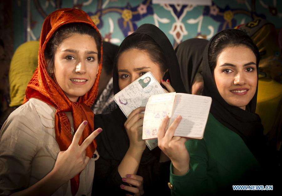 Des électrices iraniennes montrent leurs cartes d'identité avant de voter à un bureau de vote dans le nord de Téhéran, en Iran, le 14 juin 2013. Le dirigeant suprême de l'Iran, l'ayatollah Ali Khamenei, a voté à l'élection présidentielle iranienne et déclaré l'ouverture du scrutin vendredi matin. (Photo: Xinhua / Ahmad Halabisaz)