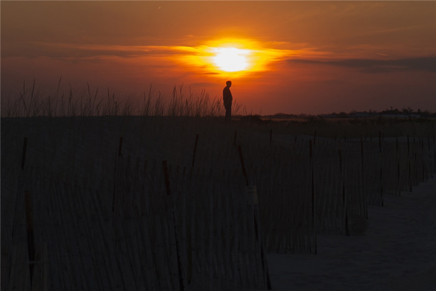 Un habitant se tient près du rivage de Breezy Point, dans l'arrondissement de Queens Beach au coucher du soleil pour le premier anniversaire de l'ouragan Sandy, à New York le 29 octobre 2013.