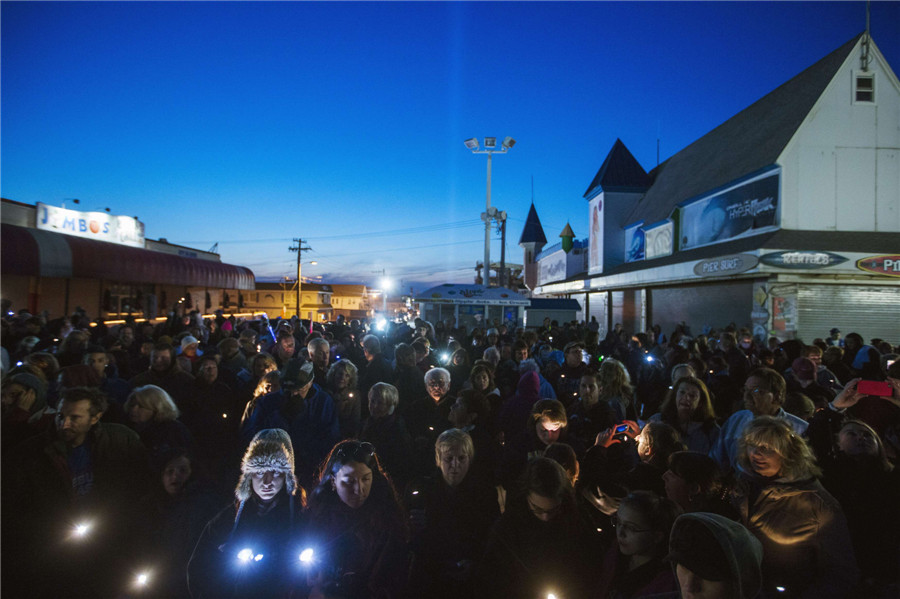 Des habitants du New Jersey participent à une manifestation d'illumination de la c?te pour le premier anniversaire de l'ouragan Sandy à Seaside Heights, dans le New Jersey, le 29 octobre 2013. Un an après que la super-tempête Sandy ait balayé la c?te Est avec des inondations record qui firent 159 morts, les résidents des communes c?tières du New Jersey et de New York, durement touchées, ont encore du chemin à parcourir pour reconstruire leurs maisons endommagées. [Photo / agences]