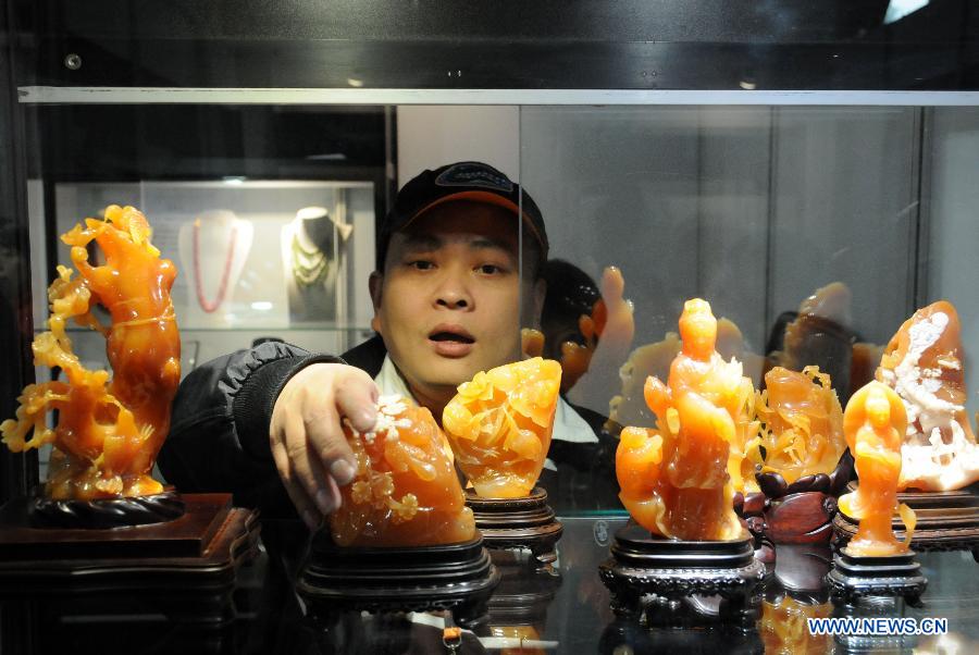 Un visiteur prend un article de bijouterie lors du Salon international du bijou et de l'accessoire 2013 à Beijing. L'exposition d'une durée de quatre jours a débuté le 13 novembre 2013. [Photo / Xinhua]