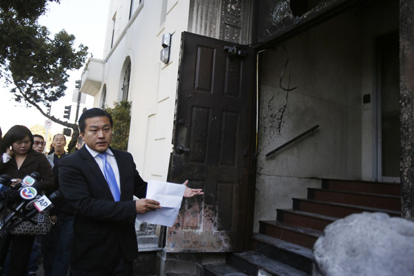 Wang Chuan, un porte-parole du consulat de Chine à San Francisco, montre une porte endommagée lors d'une conférence de presse après qu'une personne non identifiée y ait mis le feu à San Francisco, en Californie, le 2 janvier 2014. [Photo / agences]