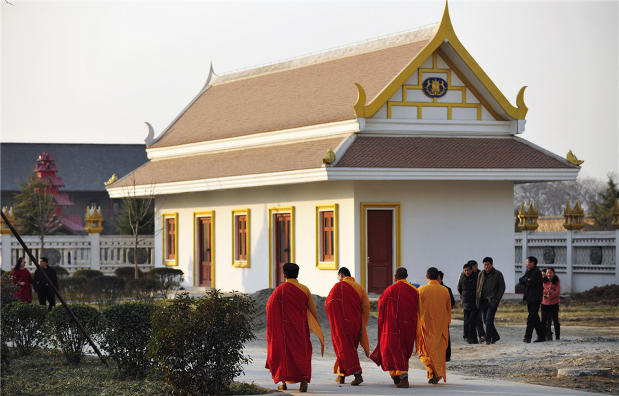 Des moines passent devant une structure bouddhiste de style tha?landais qui devrait être achevée et ouverte au public dans la première moitié de 2014, au Temple du Cheval blanc, ou Bai Ma Si, dans la ville de Luoyang, dans la province du Henan, au centre de la Chine, le 12 janvier 2014. [Photo / Asianewsphoto ]