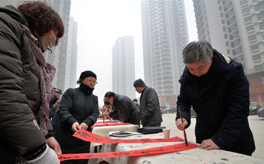 Des membres de l'association des calligraphes de la ville de Handan, dans la province du Hebei en Chine du Nord écrivent des sentences parallèles de la Fête du Printemps pour les habitants, le 17 janvier 2014. [photo / icpress.cn]